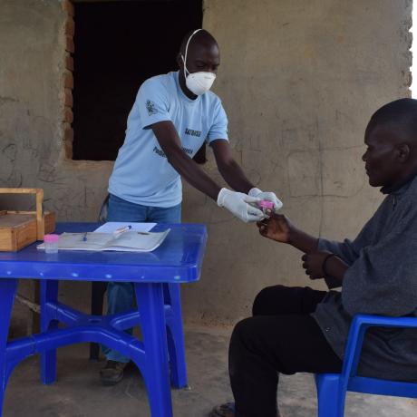 Henry receiving a sputum bottle from a TB Volunteer