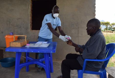 Henry receiving a sputum bottle from a TB Volunteer