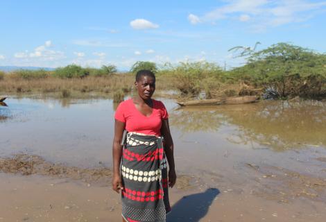 Esnert Thaison standing dejectedly in front of her submerged crop field.