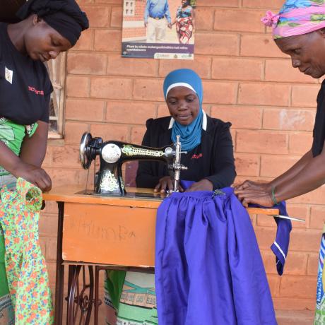 Mkumba Support Mother Group members sewing clothes for needy children and for sale
