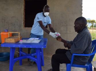 Henry receiving a sputum bottle from a TB Volunteer